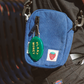 Blue pouch with a green 'Plant Money' tag attached to a person's bag.