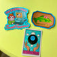 Three colorful stickers on a green surface