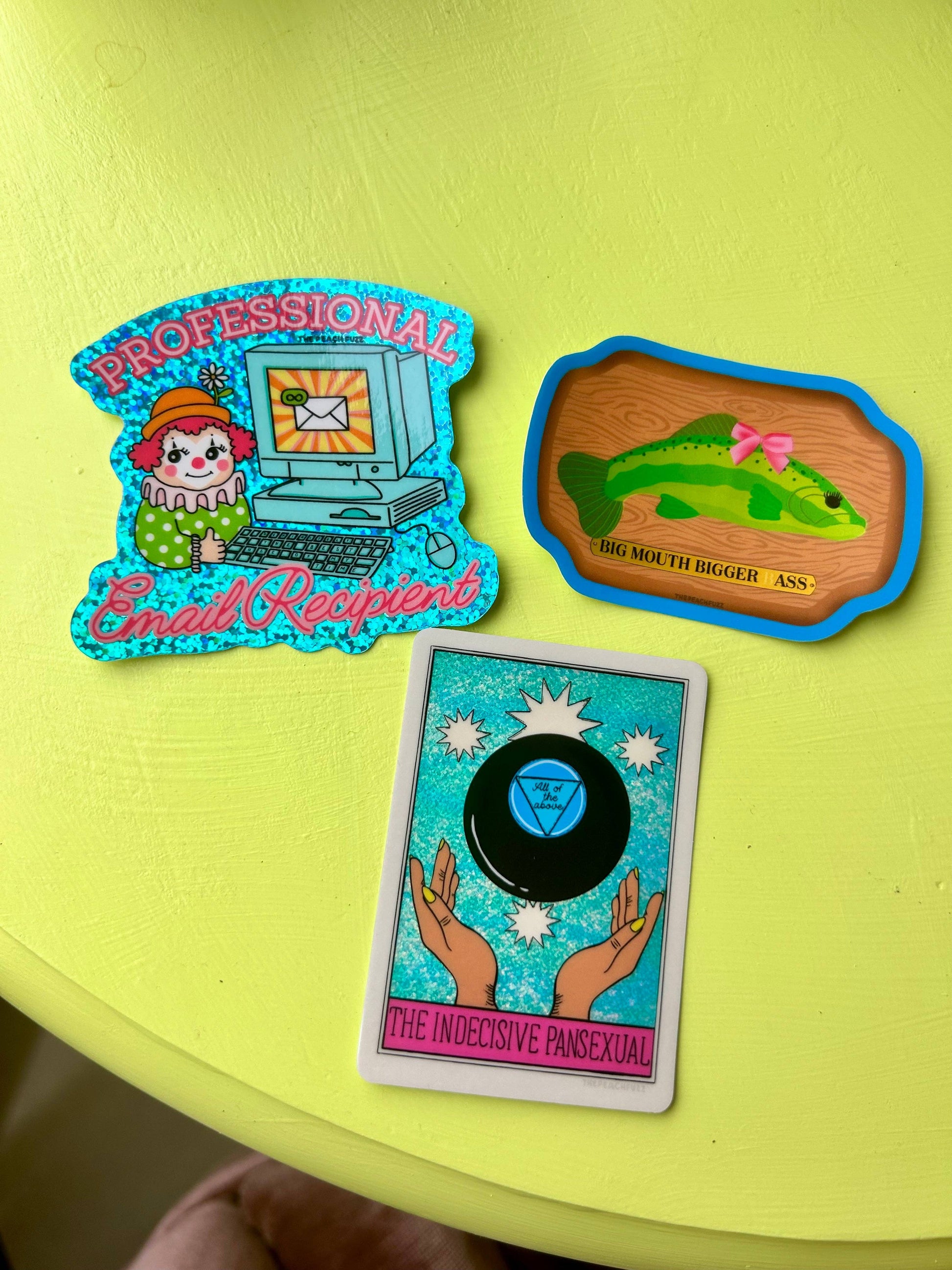 Three colorful stickers on a green surface