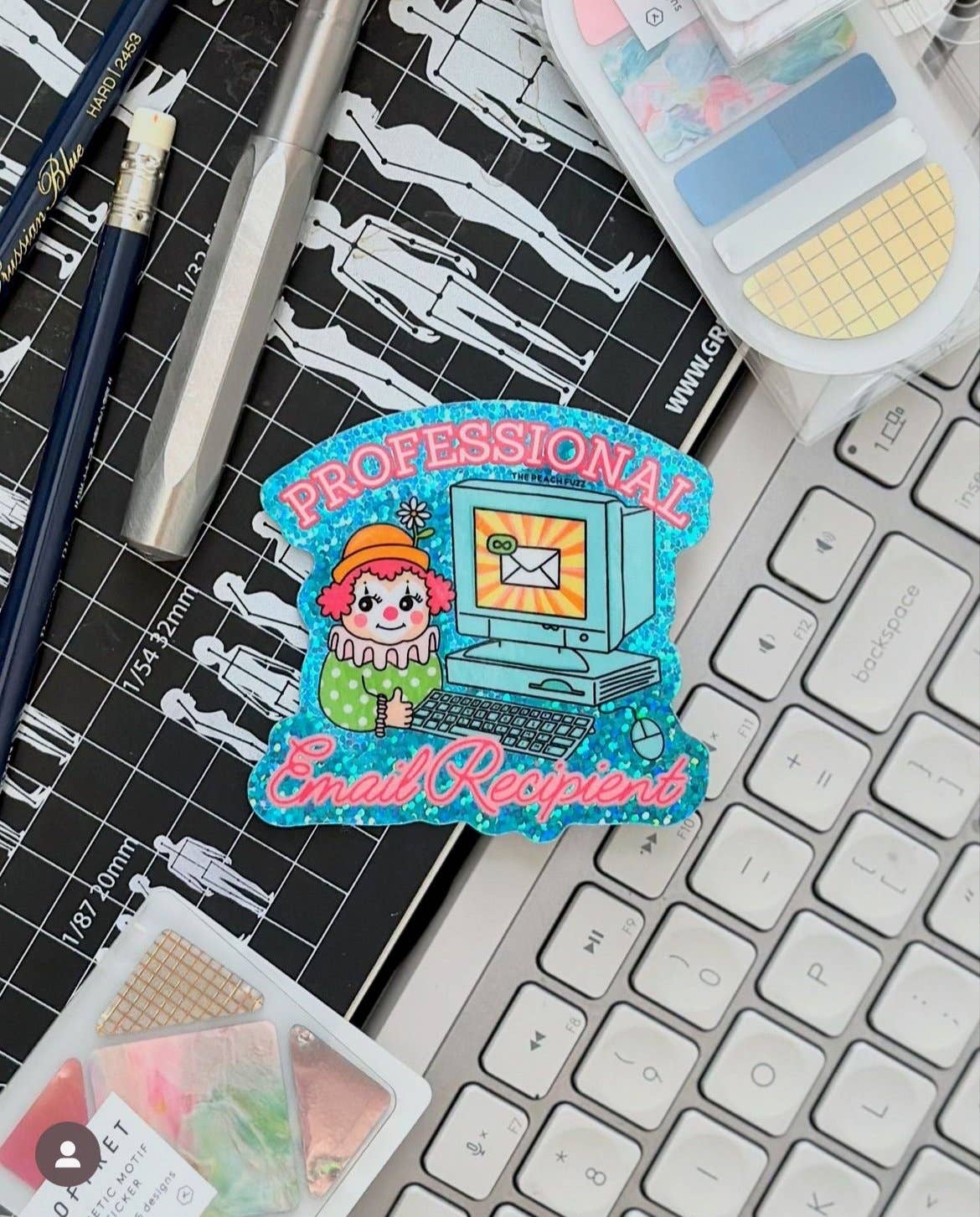 Colorful patch with cartoon character and text 'Professional Email recipient' on a keyboard and stationery items.