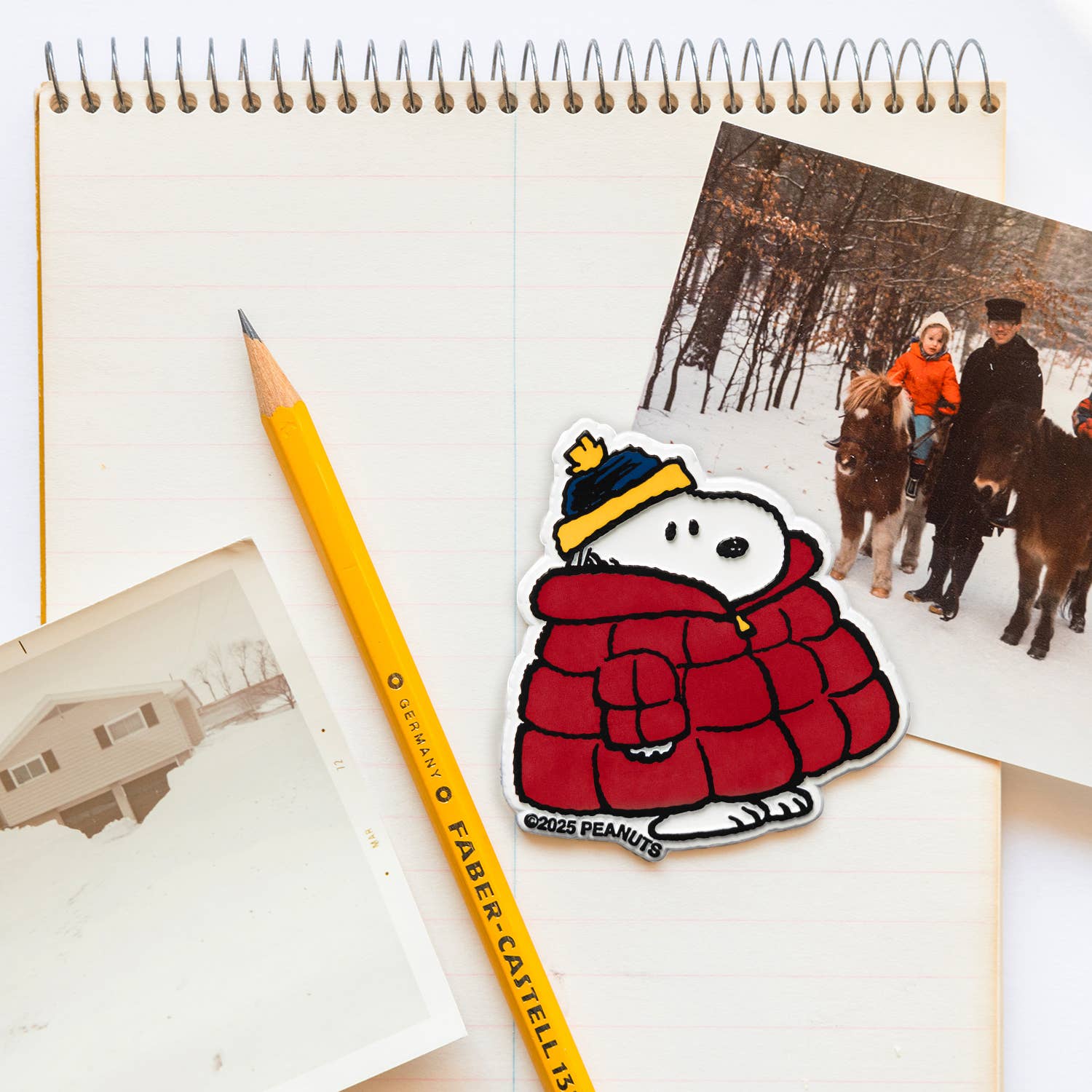 Magnet of snoopy in a red coat with a yellow pencil on a notebook