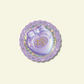 Purple Polly Pocket toy sticker on a decorative purple and glitter circular base with a light beige background
