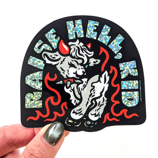 Sticker with a goat and text 'Raise Hell, Kid' held by a hand.