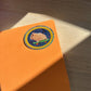 Orange notebook with a colorful sticker of a hamster on a wooden surface
