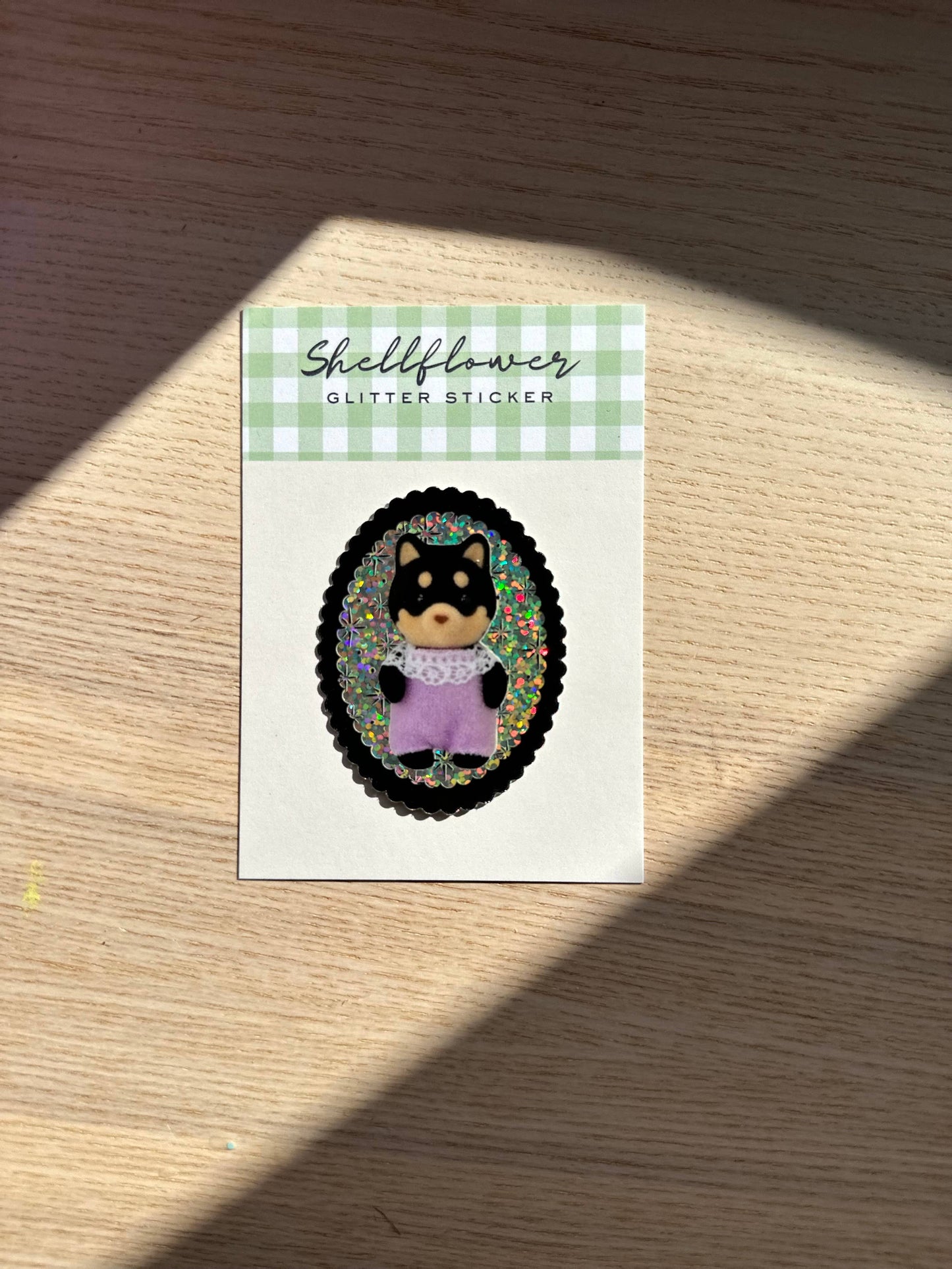 Sticker with a shiba inu illustration on a green and white checkered card, placed on a wooden surface.