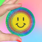 Hand holding a sicker with a smiley face on a gradient background