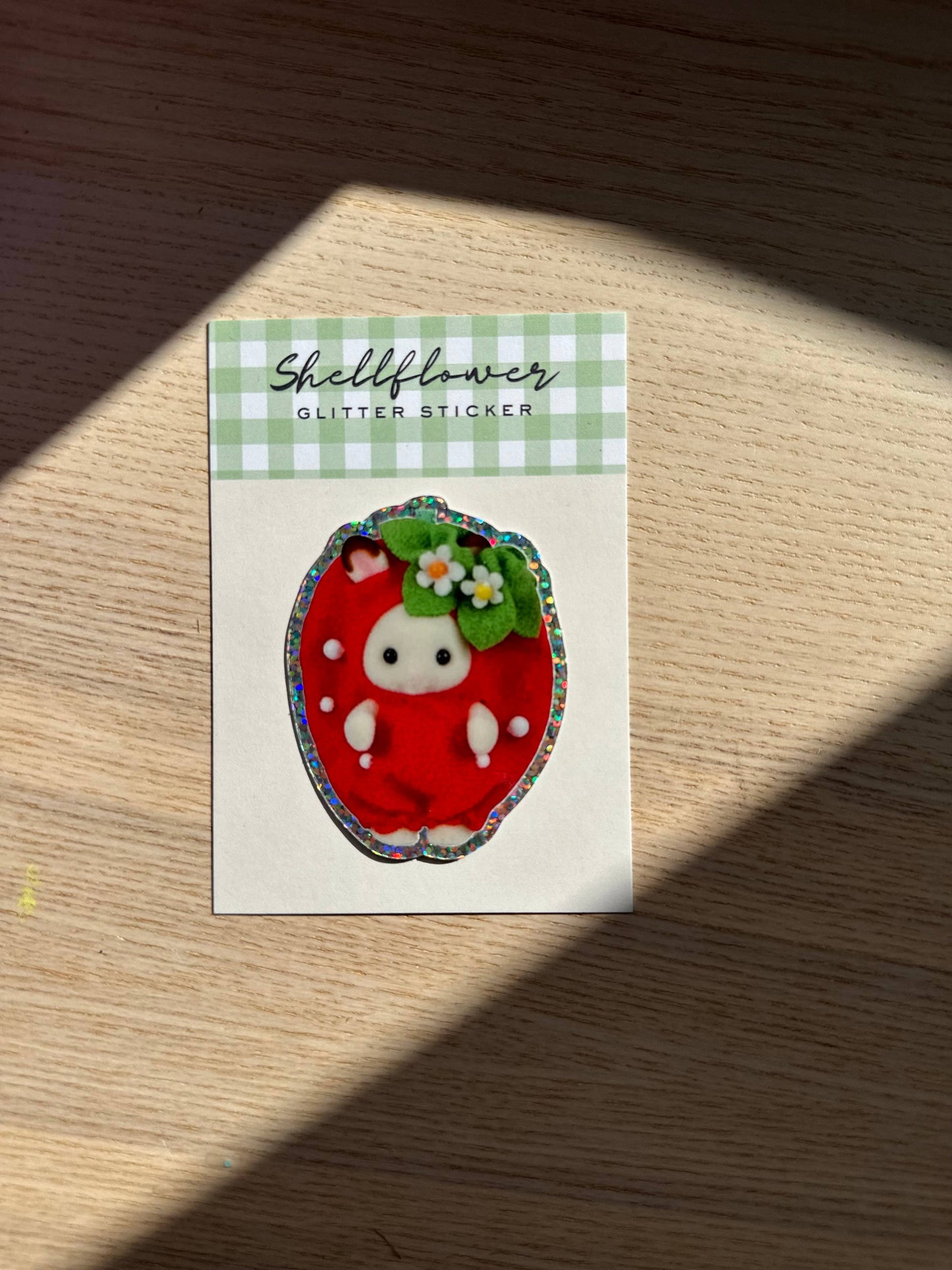 Shellflower glitter sticker on a wooden surface