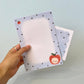 Hand holding a set of small notebooks with lion illustrations on a light blue background