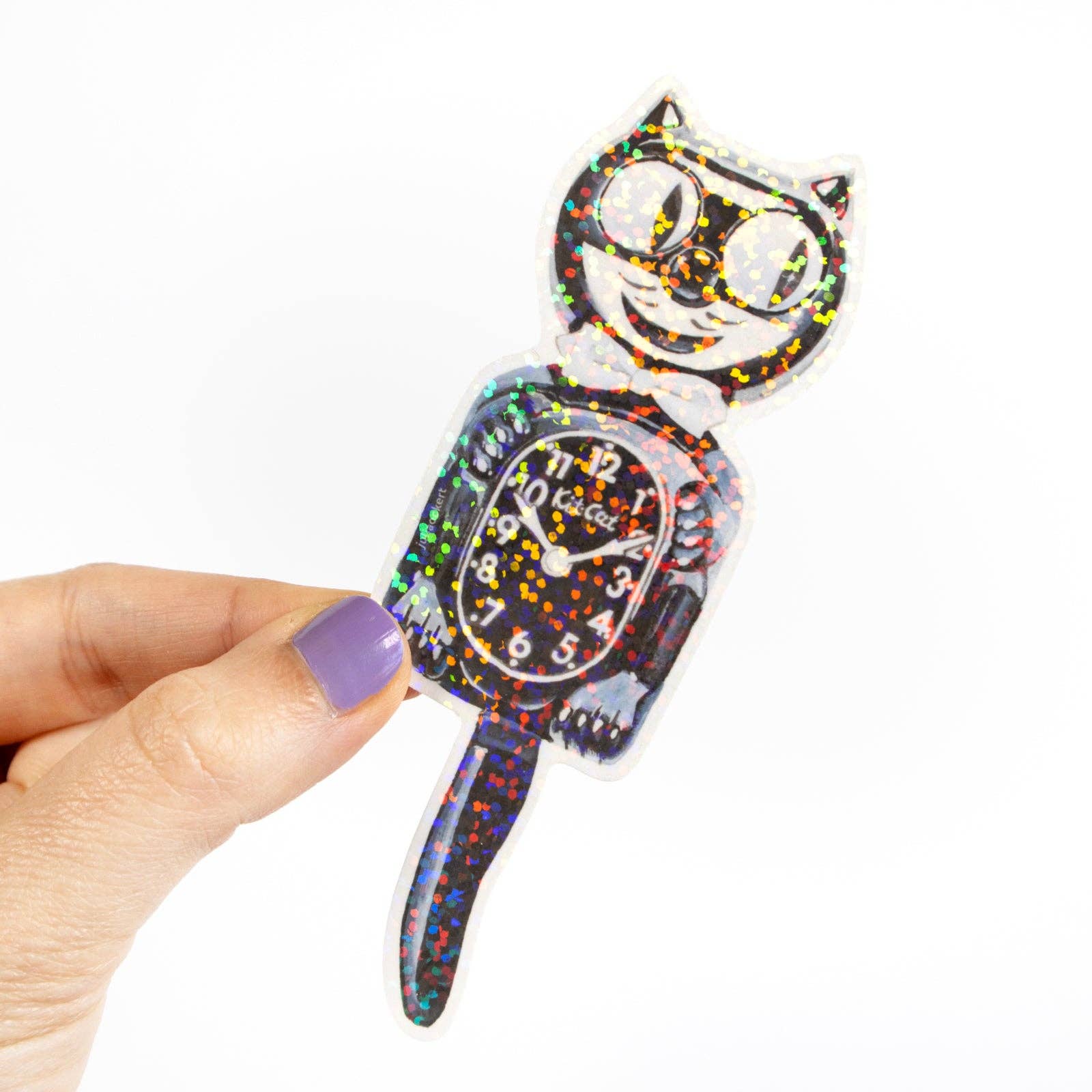Colorful cat-shaped clock held by a hand with purple nail polish on a white background
