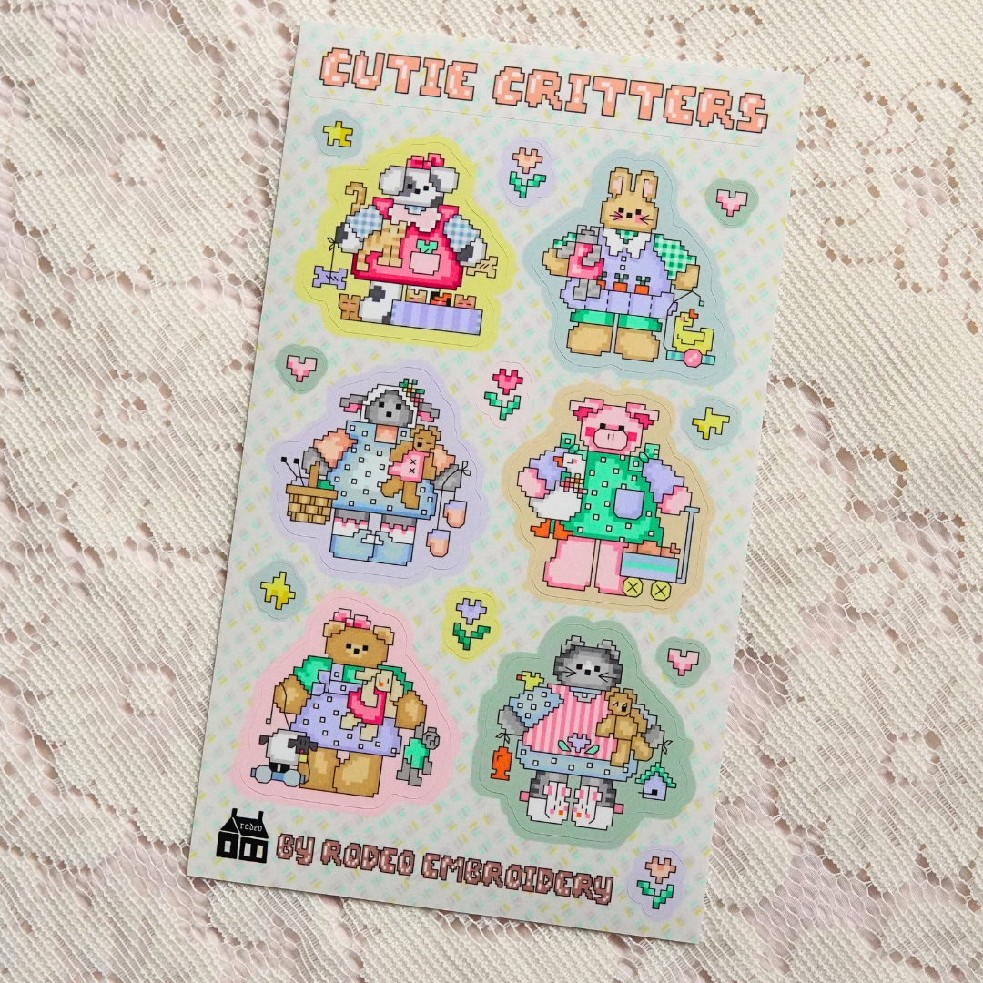 Sheet of 'Cutie Critters' stickers with cartoon animals in embroidered designs on a textured surface.