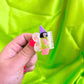 Hand holding a small fairy hair clip with a colorful background