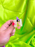 Hand holding a small fairy hair clip with a colorful background